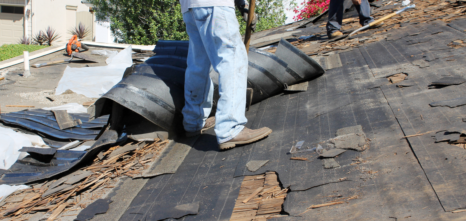 Roofing crew performing full tear-off, stripping old shingles to the deck